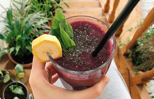 A hand holding a collagen smoothie on wooden steps